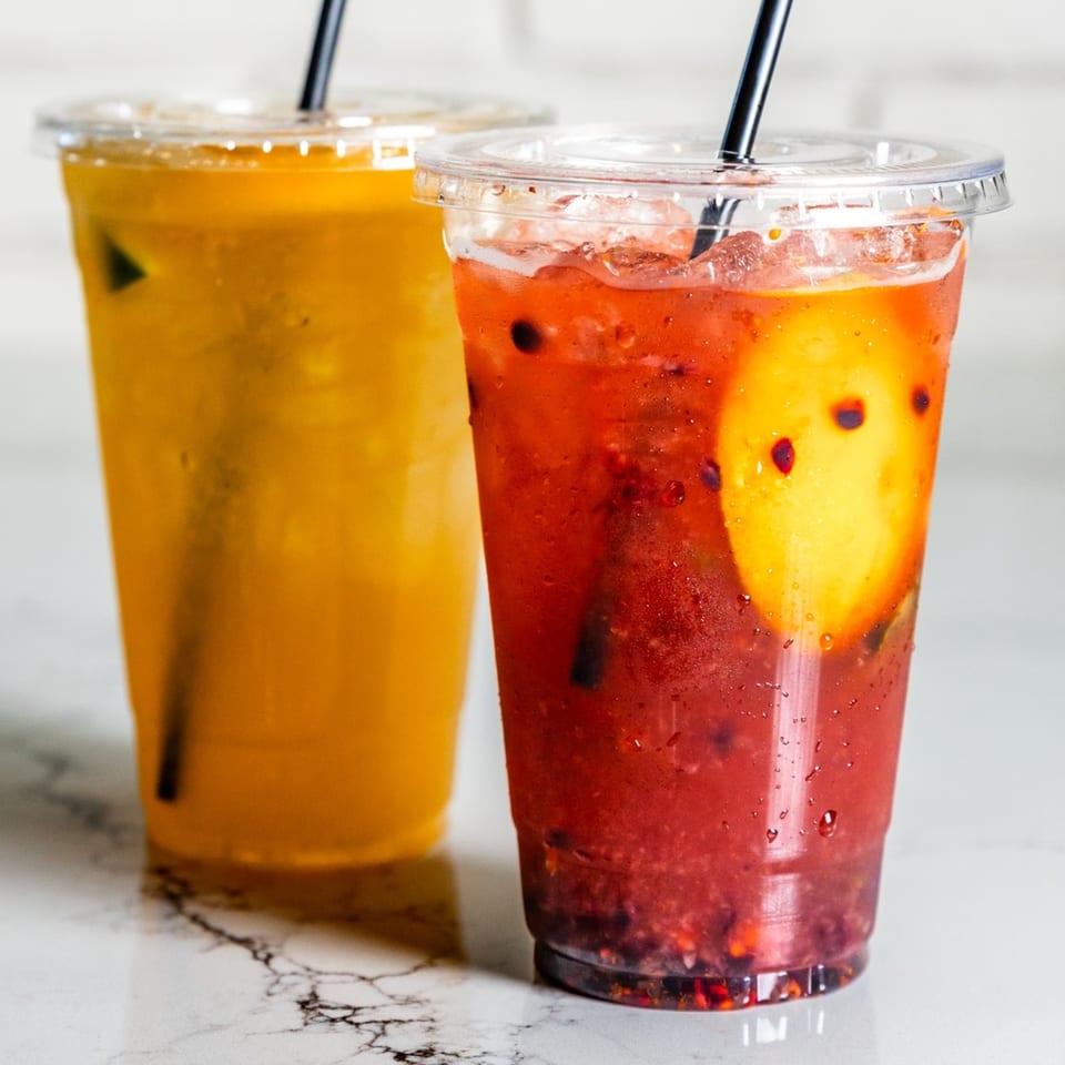 Two refreshing Federales Street Tacos drinks, one orange and one red, with ice and straws.