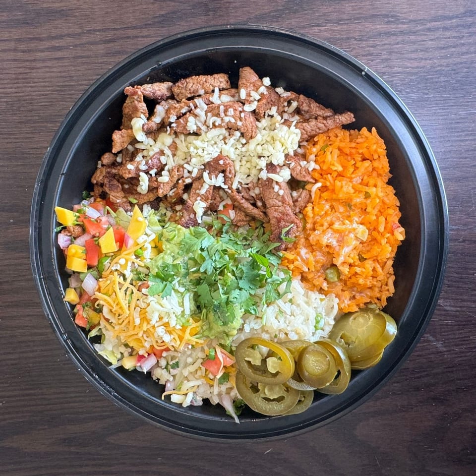 Overhead view of a Federales Street Tacos burrito bowl with steak, rice, salsa, guacamole, and jalapeños.
